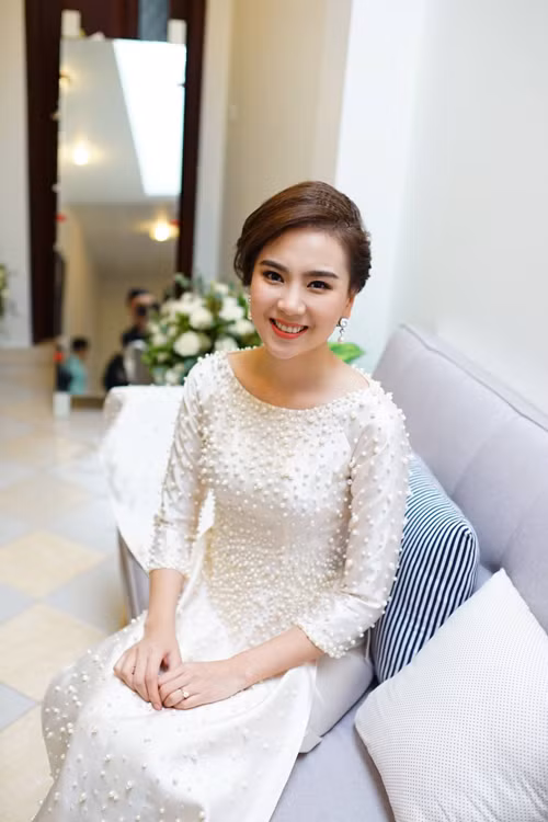 Đến giờ tốt lành, Mai Ngọc thay đổi trang phục để chuẩn bị đón nhà trai. Cô mặc một chiếc áo dài khác mang sắc trắng tinh khôi được điểm xuyết bằng hàng 2.000 viên ngọc trai đủ kích thước. Đây là một điểm nhấn nữa giúp lễ ăn hỏi của nữ MC xinh đẹp trở nên đẳng cấp, ấn tượng hơn.