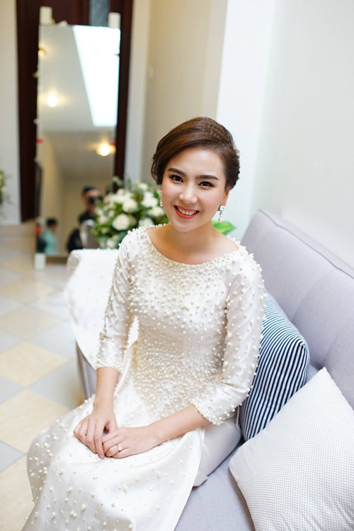 Đến giờ tốt lành, Mai Ngọc thay đổi trang phục để chuẩn bị đón nhà trai. Cô mặc một chiếc áo dài khác mang sắc trắng tinh khôi được điểm xuyết bằng hàng 2.000 viên ngọc trai đủ kích thước. Đây là một điểm nhấn nữa giúp lễ ăn hỏi của nữ MC xinh đẹp trở nên đẳng cấp, ấn tượng hơn.