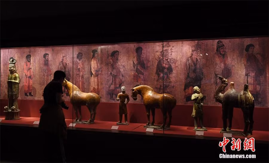 Trong số hơm 400 cổ vật, nhiều món đồ gốm, hiện vật bằng vàng, ngọc bích, lụa, tranh vẽ... gây được sự chú ý lớn. Trong ảnh là một khách tham quan chăm chú ngắm nhìn những bức tượng gốm tráng men 3 màu thời nhà Đường.