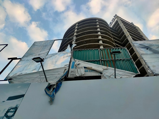 Bảng thông tin dự án phía dưới chân công trình bị phai màu, rách nát tơi tả. 