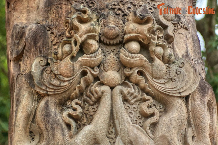 Phần đỉnh cột được chạm nổi đôi rồng theo đồ án “lưỡng long hiến châu”. Đầu rồng nhô cao chầu nhau, miệng ngậm ngọc, được chạm khắc với những hoa văn vô cùng tinh xảo. Chân trước cặp rồng chụm lại dâng một viên ngọc cùng cỡ với viên ngọc ngậm ở miệng.