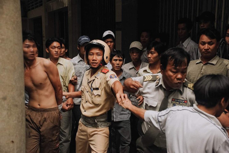 Thiếu úy CSGT khống chế, đưa tên cướp ra khỏi hẻm để bàn giao lực lượng Công an địa phương. Lúc này, một số người quá khích lao vào định tấn công tên cướp nhưng Thiếu úy Thanh đã ra sức ngăn cản, bảo đảm an toàn cho đối tượng. (Ảnh Dave MacMillan)