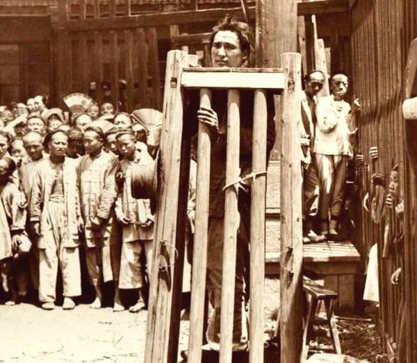 Phạm nhân bị nhốt trong trạm lồng tại một địa điểm công cộng. Ảnh chụp năm 1900.