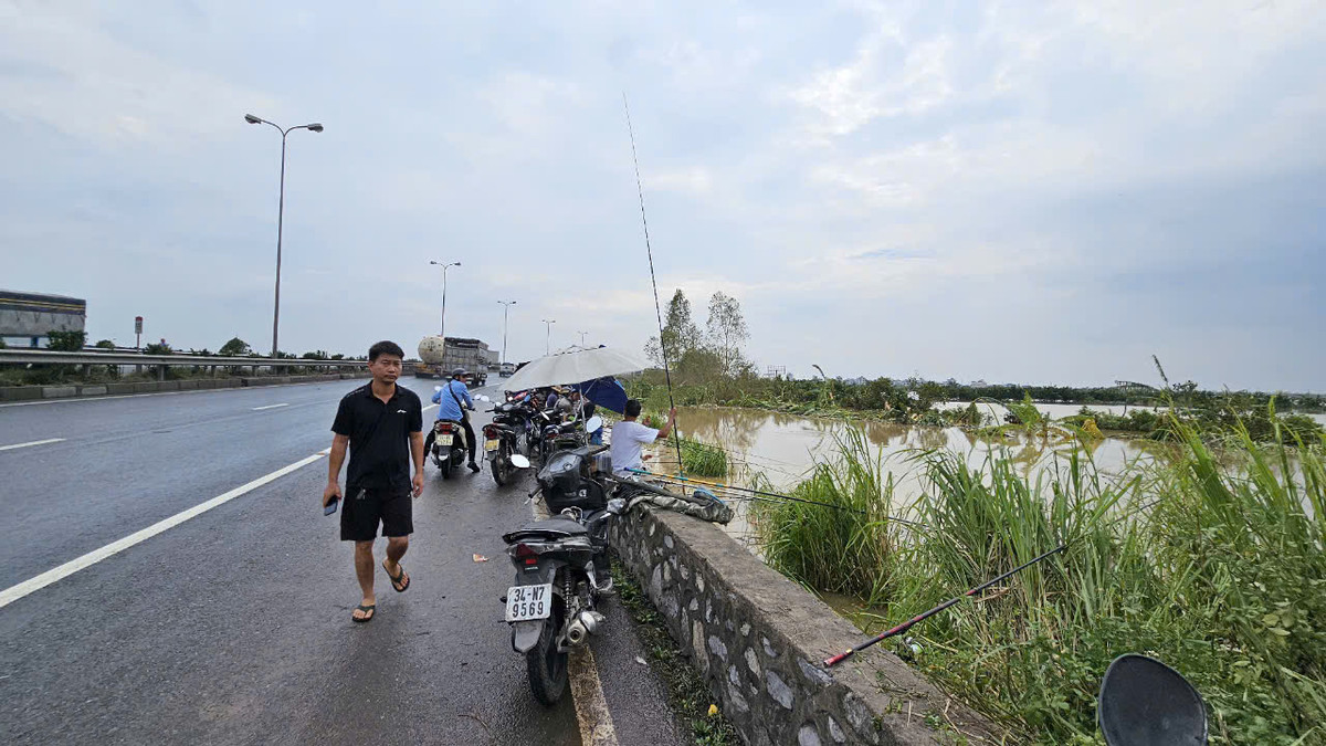 Nhiều người ngồi trên hộ lan Quốc lộ 5 để câu cá.