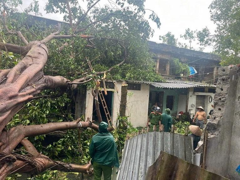 Lực lượng công an hỗ trợ người dân dọn dẹp cây đổ sau bão.