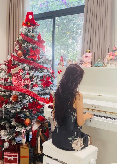 Vân Hugo đánh đàn bên cây thông Noel dịp Giáng sinh.