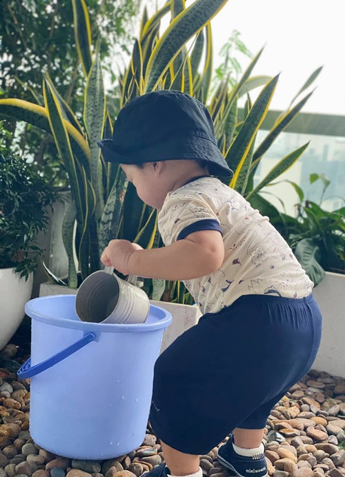 Con trai thứ hai của Thu Thảo bắt chước chị gái tưới cây cảnh. Ảnh: FB Thu Thảo.
