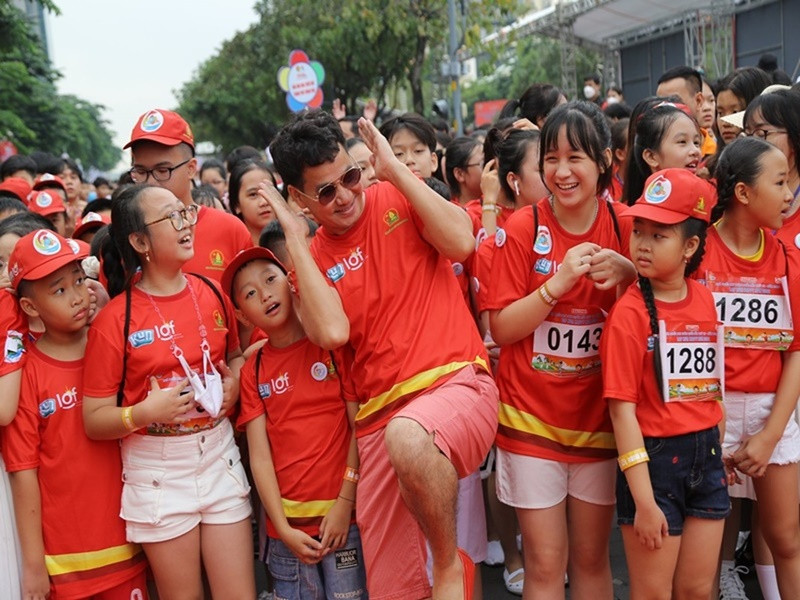 Nam nghệ sĩ tạo dáng xì-tin cùng các em nhỏ trong một hoạt động ngoài trời.