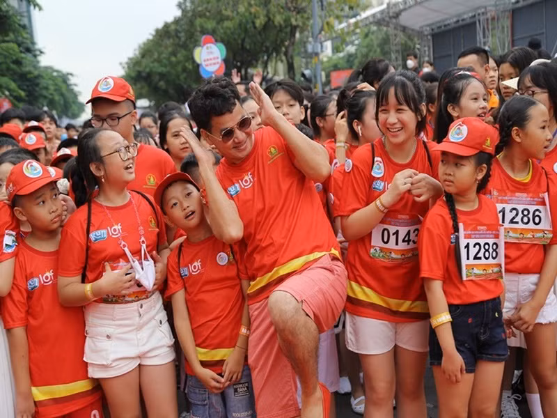 Nam nghệ sĩ tạo dáng xì-tin cùng các em nhỏ trong một hoạt động ngoài trời.