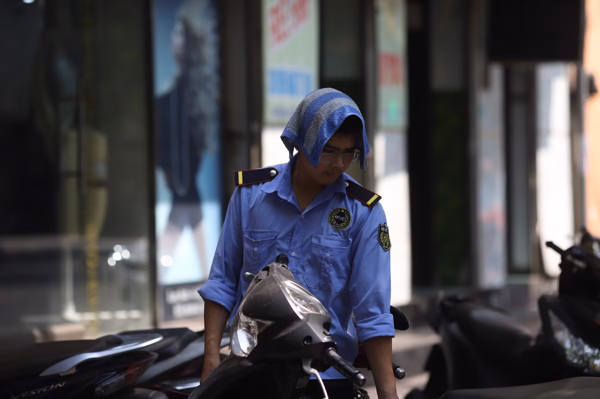 Những người làm việc ngoài đường và chiếc khăn ướt trùm đầu cũng là phương pháp giảm nhiệt, tránh nóng.