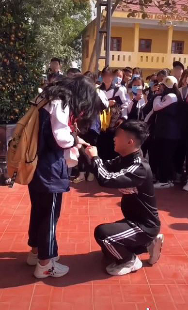 Trước đó, cư dân mạng từng tranh cãi về clip khác khi nữ sinh được cầu hôn ngay tại trường. Cụ thể, trong bộ quần áo thể dục của học sinh cấp 3, cậu học trò bảnh bao đã mạnh dạn nắm lấy tay "crush" rồi quỳ xuống trong sự ngỡ ngàng của mọi người. Ảnh: Tiin.vn