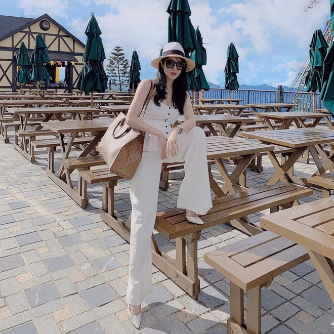 Hình ảnh cá tính của Diệp Lâm Anh với "cây trắng" (áo hở vai và quần ống rộng) trong những tháng đầu thai kỳ. Tô điểm cho vẻ ngoài hiện đại của chân dài 8X là mũ cói, túi xách khổ lớn của LV.