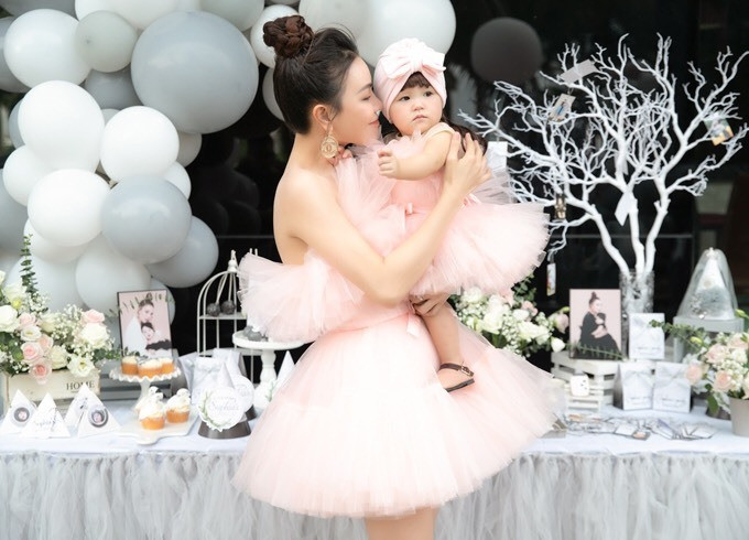 Hai mẹ con diện trang phục hồng phấn cùng tông tiếp đón quan khách. Nữ ca sĩ thời gian qua cũng ngưng hoạt động ở làng giải trí, tập trung nuôi con với sự hỗ trợ của mẹ và chị gái.