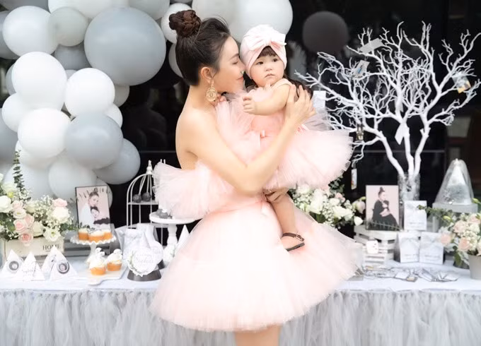 Hai mẹ con diện trang phục hồng phấn cùng tông tiếp đón quan khách. Nữ ca sĩ thời gian qua cũng ngưng hoạt động ở làng giải trí, tập trung nuôi con với sự hỗ trợ của mẹ và chị gái.