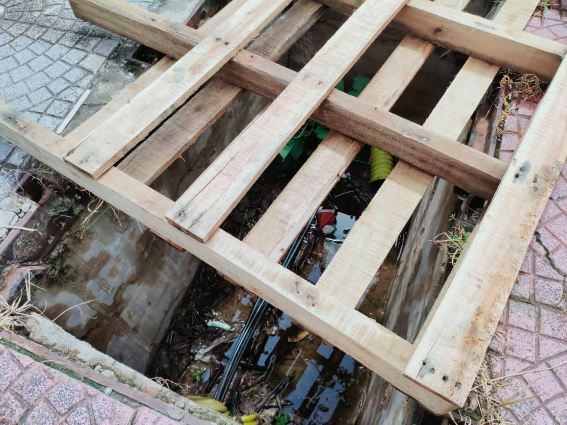 Một hố cáp mất nắp được đậy tạm bằng miếng gỗ.
