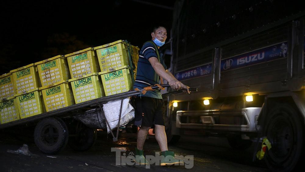 Chợ Long Biên là một chợ trực thuộc quận Ba Đình, Hà Nội. Sở dĩ gọi tên chợ như vậy là bởi vì nó nằm ngay dưới chân cây cầu lịch sử Long Biên – chứng nhân cho bao thăng trầm của Thủ đô Hà Nội. Ảnh: Những người làm nghề cửu vạn tại chợ nhanh chóng kéo hàng chục thùng rau, củ, quả từ điểm đỗ xe tải vào trong chợ. 