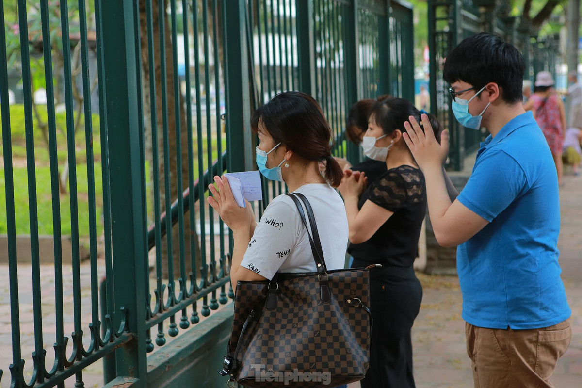 Phụ huynh cẩn thận mang theo cả giấy ghi số báo danh của con em mình để đọc cầu may.