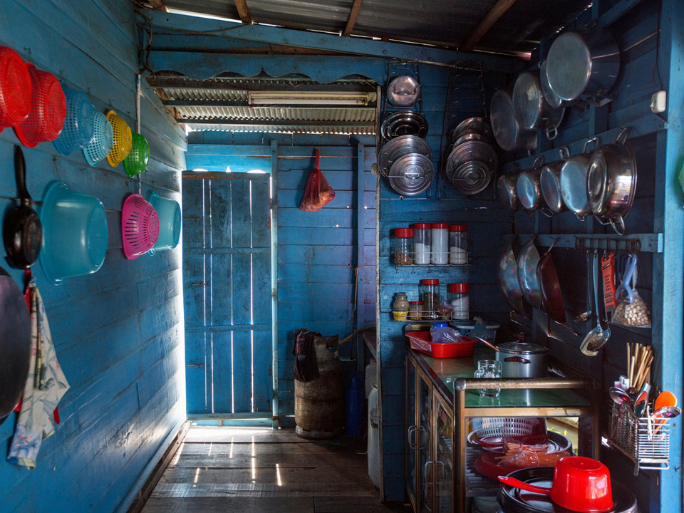 Đây là một gian bếp, trông rất bình thường trừ việc nó nằm trên mặt nước, chính xác là nằm trên Biển Hồ, Campuchia. Như mọi căn nhà khác ở đây, nó đối mặt với hàng loạt nguy cơ mà dòng nước mang lại, đặc biệt trong mùa mưa. Vào cuối tháng 7, lúc nào cũng có việc cho Taing Hoarith làm với ngôi nhà của ông. Khi thì ông phải sửa lại bức tường lợp bằng lá cọ đã bị bão làm hư, khi thì ông phải dọn dẹp đám cây mọc trong nước. Đôi khi ông phải lặn xuống bên dưới căn nhà, miệng ngậm một ống cao su và chèn vào những hũ xi măng đang giữ căn nhà đứng vững trên nước. Ảnh: New York Times