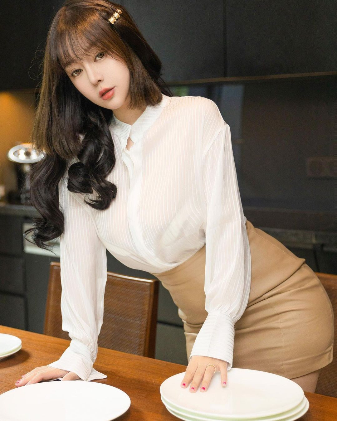 Chiếc áo sơ mi kẻ mỏng màu trắng phối cùng váy da màu nâu nhạt tôn được toàn bộ vóc dáng của hot girl xinh đẹp.