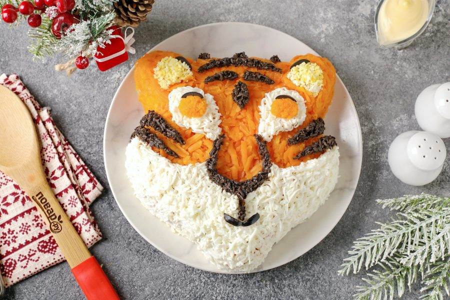 Bước 11: Lòng đỏ xay mịn còn thừa tạo hình phần trong tai. Tạo hình con ngươi bằng cà rốt bào nhuyễn. Cắt nhỏ olive xếp thành râu. Thêm hai chấm tròn hạt olive làm mắt.