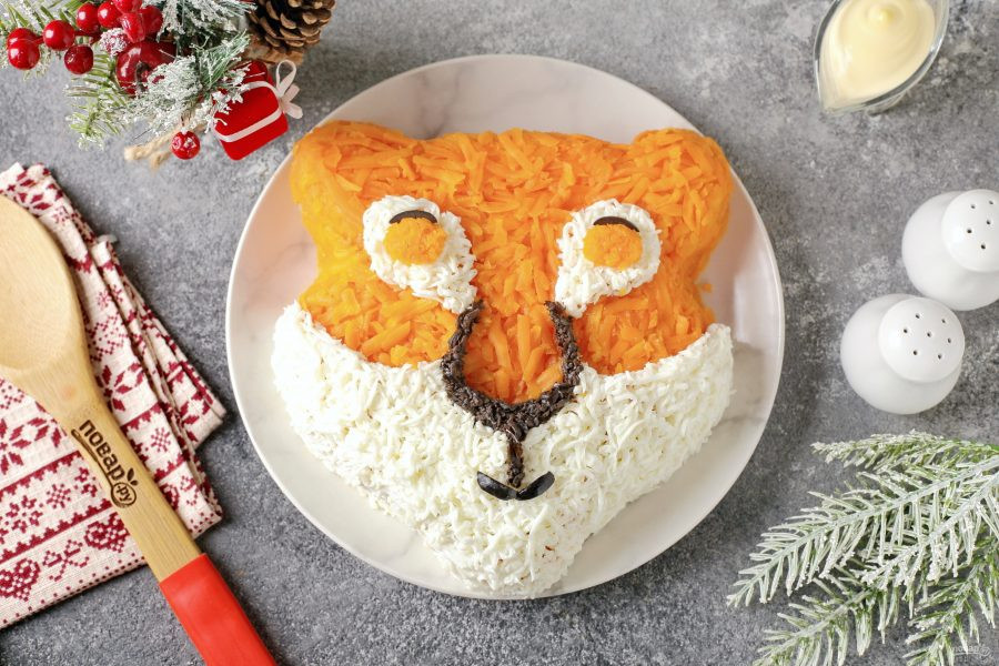 Bước 10: Xay trái olive rồi tạo hình mũi, sọc vằn ở má và trán bằng nguyên liệu này. Tạo hình con ngươi bằng cà rốt bào nhuyễn.