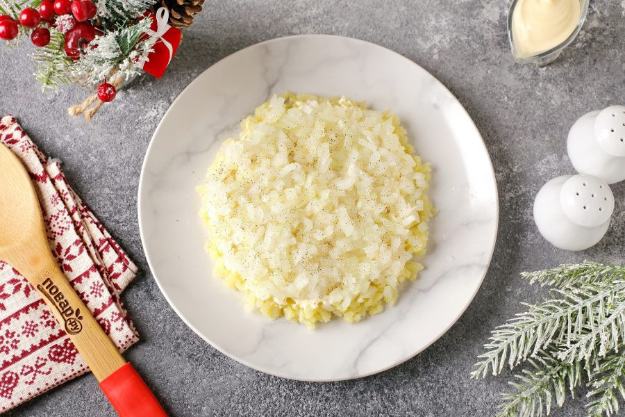 Bước 2: Đặt khoai tây luộc đã bào thô vào lớp đầu tiên. Quết từng lớp với sốt mayonnaise mỏng, thêm muối và tiêu cho vừa ăn. Bước 3: Hành tây cắt miếng vuông nhỏ, trụng qua nước sôi cho hết đắng rồi xếp thành lớp thứ hai.