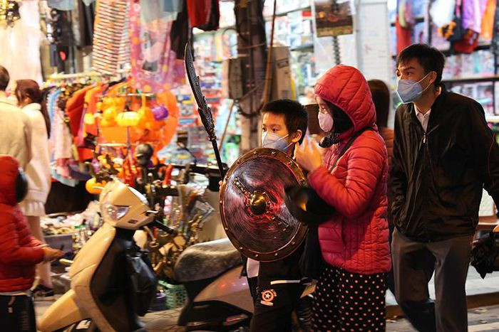 Một em nhỏ được bố tranh thủ trời tạnh mưa đưa tới phố Hàng Mã mua mặt nạ vào ngày cuối tuần.