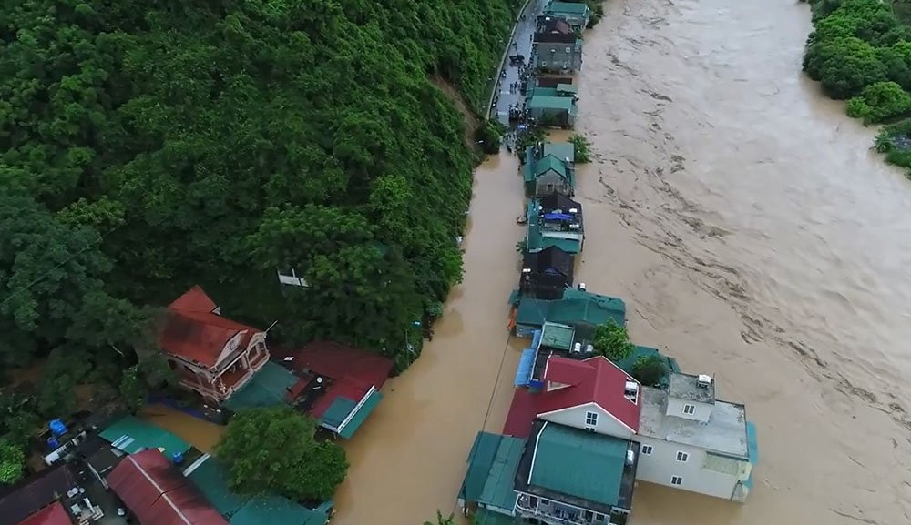 Nước lũ cuồn cuộn và những ngôi nhà chênh vênh bên sông