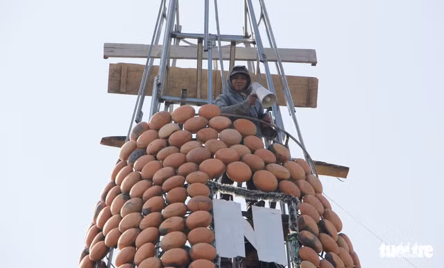 Giàn giáo được dựng bên trong thân cây thông Noel để đưa nồi đất lên cao lắp ráp - Ảnh: DOÃN HÒA.