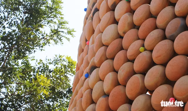 Do khoảng cách từ mặt đất lên ngọn cây thông cao 25m nên người dân phải dùng loa điều chỉnh đưa vật liệu lên - Ảnh: DOÃN HÒA.