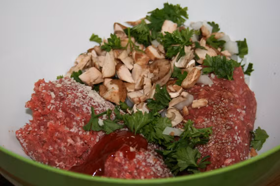 Tiếp theo, xắt nhỏ phần lõi hành tây và trộn vào bát với thịt bò, rau mùi tây, nấm, đường nâu, bánh mì. Trộn đều hỗn hợp này. Ảnh: BDT.