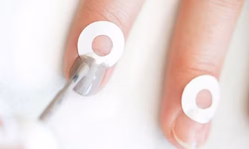 5. Tô móng hình trăng lưỡi liềm: Bạn cũng có thể tự làm móng hình trăng lưỡi liềm phần đầu móng. Lấy những sticker tròn khoét lỗ đặt ở vùng đuôi móng rồi sơn lên phần móng chừa ra. Khi gỡ bỏ sticker, bạn đã có một bộ móng sơn hình trăng khuyết đẹp lung linh. Ảnh: Cosmopolitan.