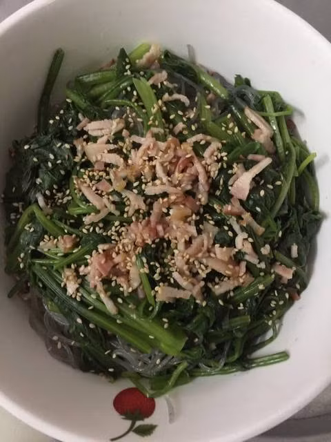 Tiếp theo, trụng cải bó xôi, vớt ra trộn chút nước tương, muối hoặc hạt nêm. Ba chỉ muối hoặc thịt heo xắt lát mỏng đem áp chảo cho chín tới rồi xắt sợi. Trộn miến, rau, thịt đã chuẩn bị ở trên lại với nhau, nêm lại chút gia vị cho vừa miệng, rắc mè rang lên mặt. Khi ăn trộn đều lại lần nữa. Ảnh: Cookpad.