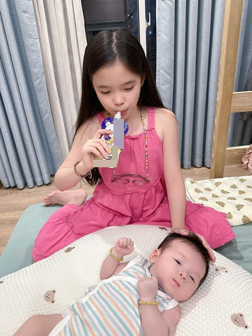 Cô nhóc xếp quần áo cho em, trông em ngủ.