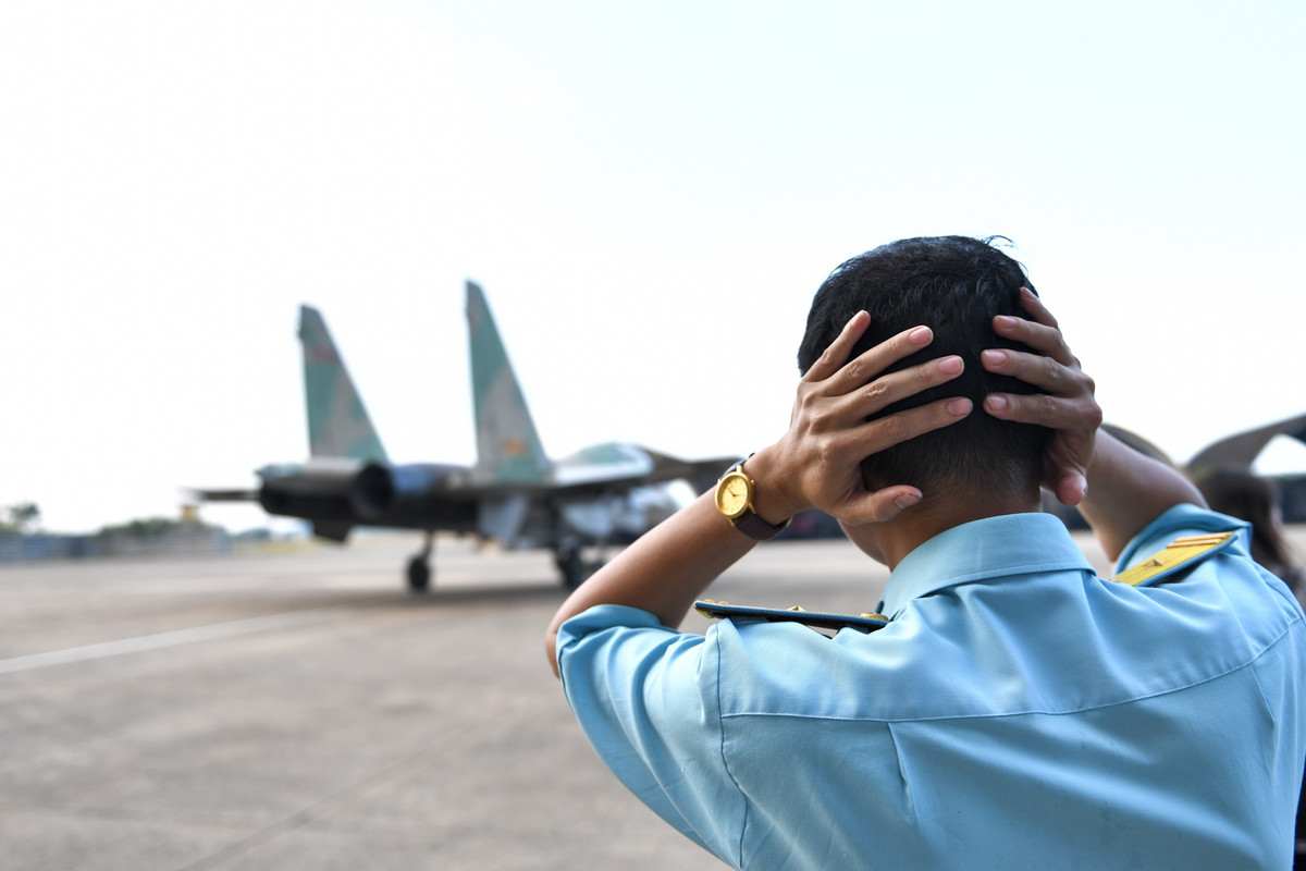 Tiếng ồn phát ra từ hai động cơ của tiêm kích Su-30MK2V khi nó được khởi động và lăn ra đường băng khiến mọi người đứng gần đều phải bịt tai vì quá lớn. Nguồn ảnh: Zingnews.