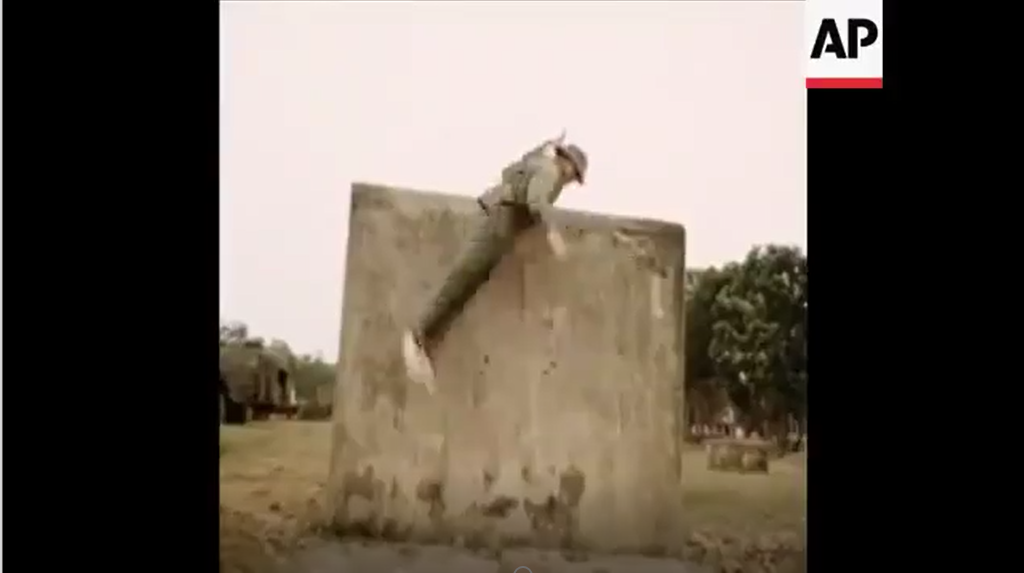 Trèo tường cao hai mét với vũ trang là một khẩu súng trường SKS trên lưng. Nguồn ảnh: AP.