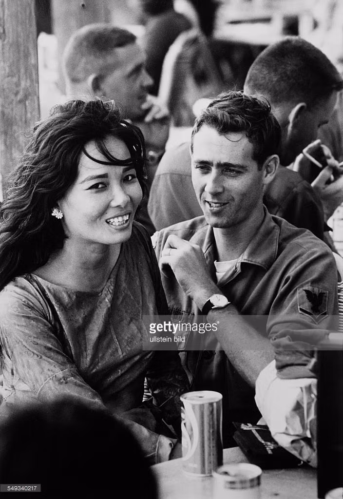 Người lính Mỹ cùng bạn gái của mình ở Vũng Tàu, tháng 4/1969. Lính Mỹ đóng quân tại các đô thị ở miền Nam Việt Nam thường tìm kiếm nhân tình tại các quán bar. Các mối quan hệ kiểu này được duy trì bằng tiền và mang tính công khai.