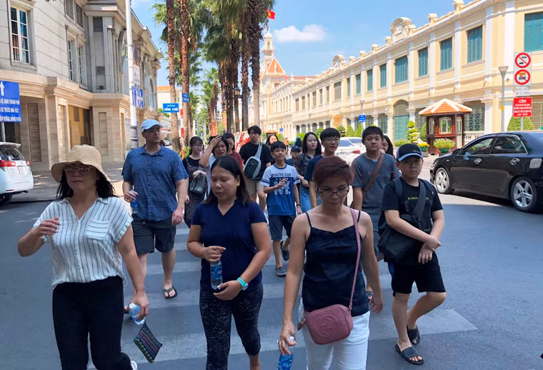 Mặc cho nắng nóng đầu hè giữa trưa ở trung tâm Sài Gòn, rất đông du khách vẫn đi lại trên đường để hòa cùng niềm vui với người dân.