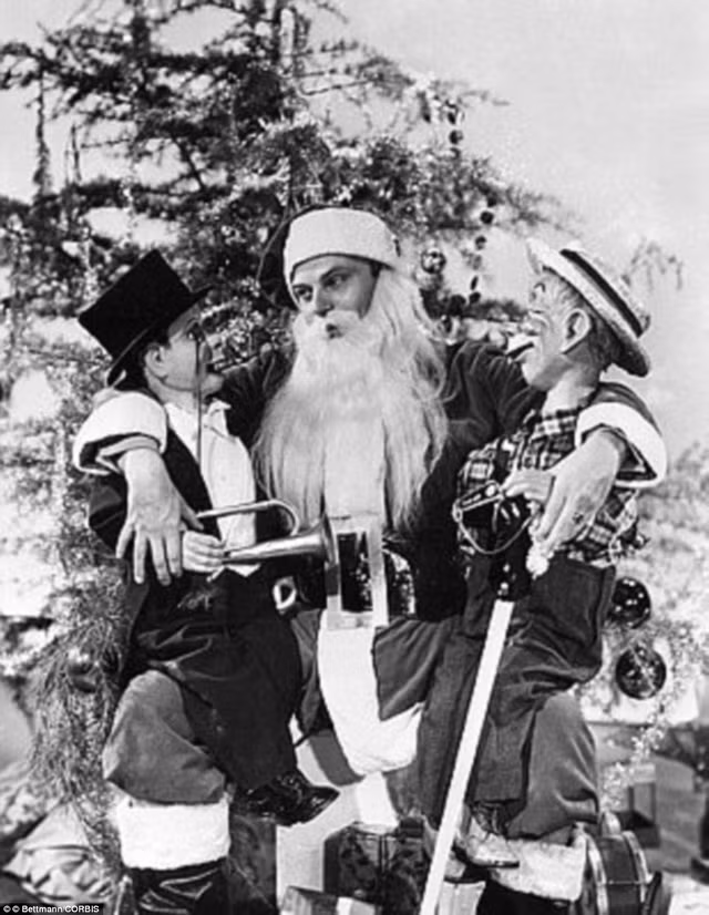 Một ông già Noel chụp ảnh trước cây thông lớn.