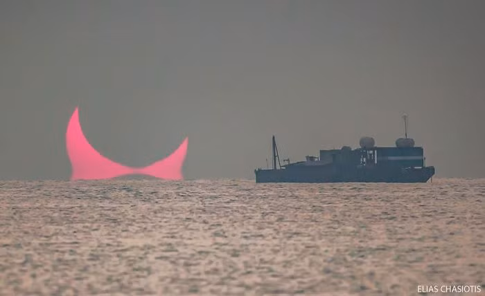 Bức ảnh của nhiếp ảnh gia Elias chụp lại khoảnh khắc Mặt trời bị Mặt trăng che khuất một phần vào lúc bình minh. Theo đó, hình ảnh Mặt trời nhô lên khỏi mặt biển trông giống sừng quỷ.