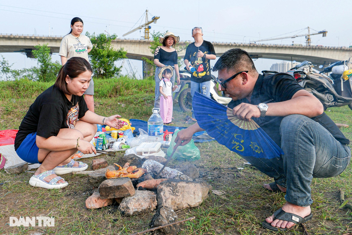 Anh Hùng (32 tuổi, Hoàng Mai, Hà Nội), cho biết: "Ngày nghỉ lễ, mình cùng người thân ra bãi giữa bờ sông Hồng cắm trại nướng đồ ăn. Nay ở đây đông người nên mình di chuyển sát chân cầu Vĩnh Tuy mới có chỗ đẹp để hạ trại".