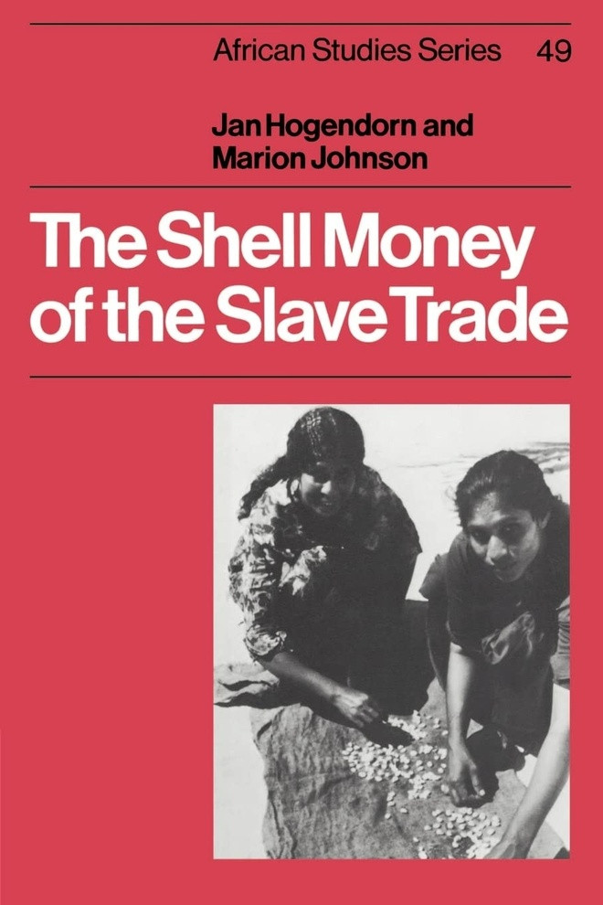 Shell money of the slave trade của Jan Hogendoorn và Marion Johnson. Vỏ sò Cowrie, ngôi nhà màu trắng bóng bẩy của một loài nhuyễn thể, chính là sự khẳng định đầu tiên của thế giới giàu có. Loại vỏ sò này được thu hoạch ở Maldives, bán ở Bengal, vận chuyển đến châu Âu (chủ yếu là Hà Lan và Anh) và được dùng để mua nô lệ ở Tây Phi. Vỏ sò này cũng đã đi xuyên Đại Tây Dương: một chiếc vỏ sò được tìm thấy tại điền trang của Thomas Jefferson trong khi một số lượng lớn được phát hiện gần các chợ nô lệ ở Virginia và một số vẫn được người Brazil gốc Phi sử dụng cho đến ngày nay để xem bói. Vai trò ghê gớm đó khiến Cowrie trở thành một trong những loại tiền quan trọng nhất còn được tìm thấy trong lịch sử. Jan Hogendoorn và Marion Johnson đã theo dõi câu chuyện này từ những lời kể đầu tiên của các du khách Ả Rập cho đến sự biến mất vào cuối những năm 1960 - thời điểm nó chỉ tồn tại ở những vùng hẻo lánh ở nông thôn Tây Phi. Ảnh: Amazon.
