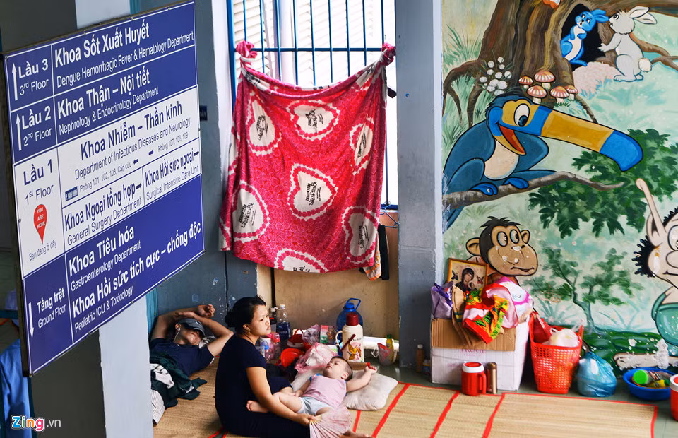 Phụ huynh đưa con ra hành lang để nghỉ tạm vì phòng bệnh quá ngột ngạt bởi tiếng la khóc của một số bệnh nhi khác.