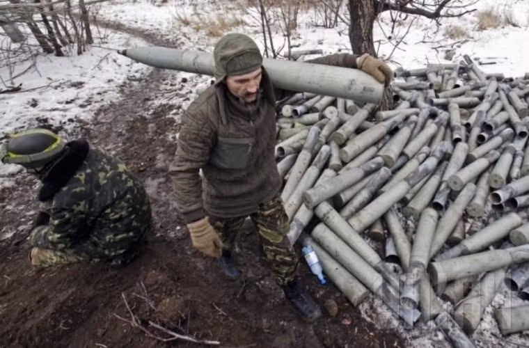 Một binh sĩ khác đang vác quả rocket còn sử dụng được trong một đống vỏ đạn.