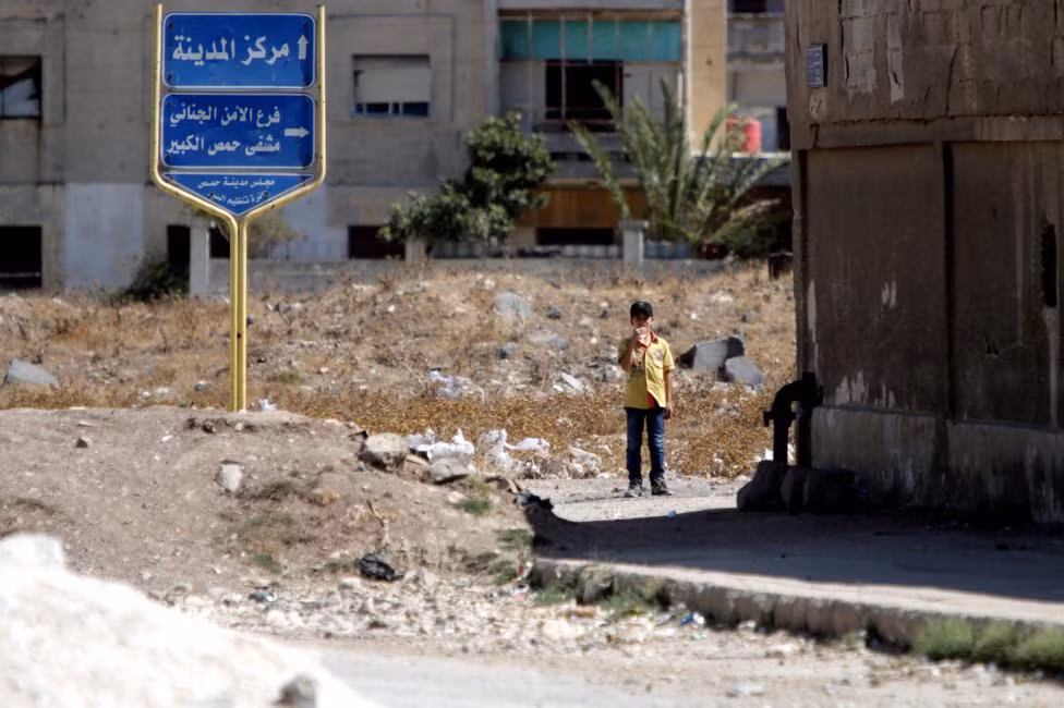 Bé trai đứng gần cửa ngõ ra vào của quận Waer.