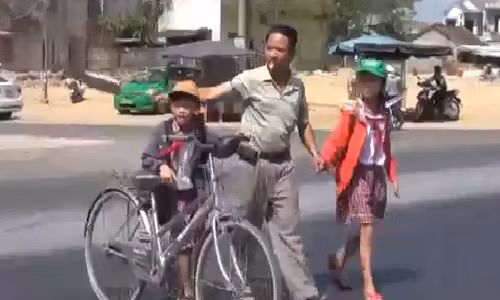 Hình ảnh anh Lê Văn Thịnh dắt trẻ nhỏ qua đường.