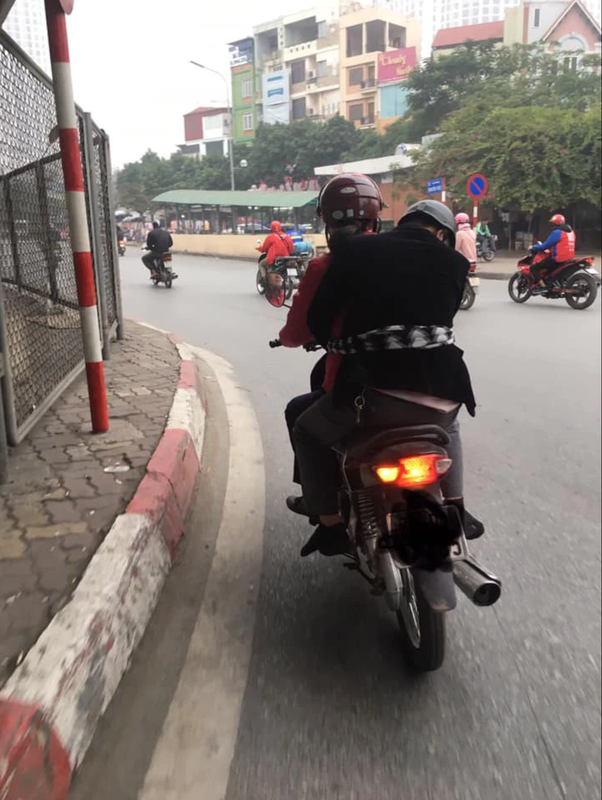 Người đàn ông này ngồi phía sau xe máy, không còn tỉnh táo và gục cả vào vai vợ.