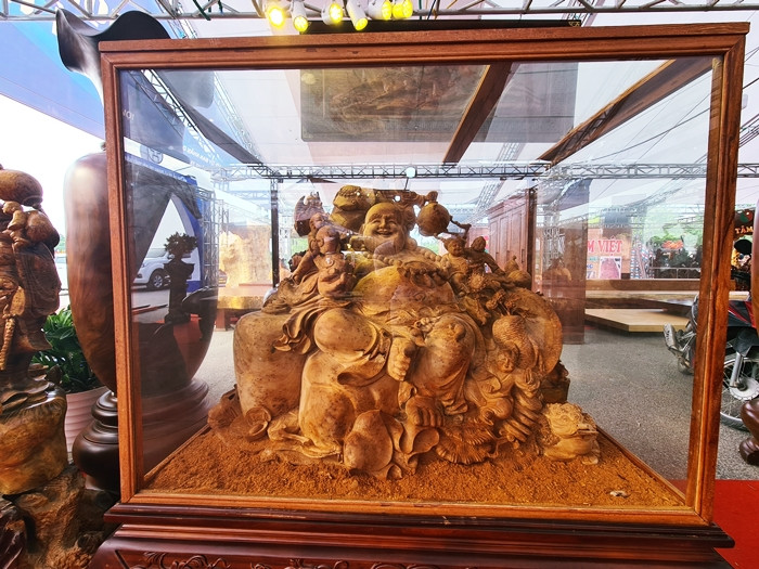 Trong gian hàng của anh Nguyễn Hợp Long còn nhiều sản phẩm đồ gỗ giá trị khác, tỏa mùi hương rất thơm, như tác phẩm “Di Lặc tựa chum ngũ tặc” được làm từ gỗ nu Ngọc Am. Giá của sản phẩm này là 800 triệu đồng.