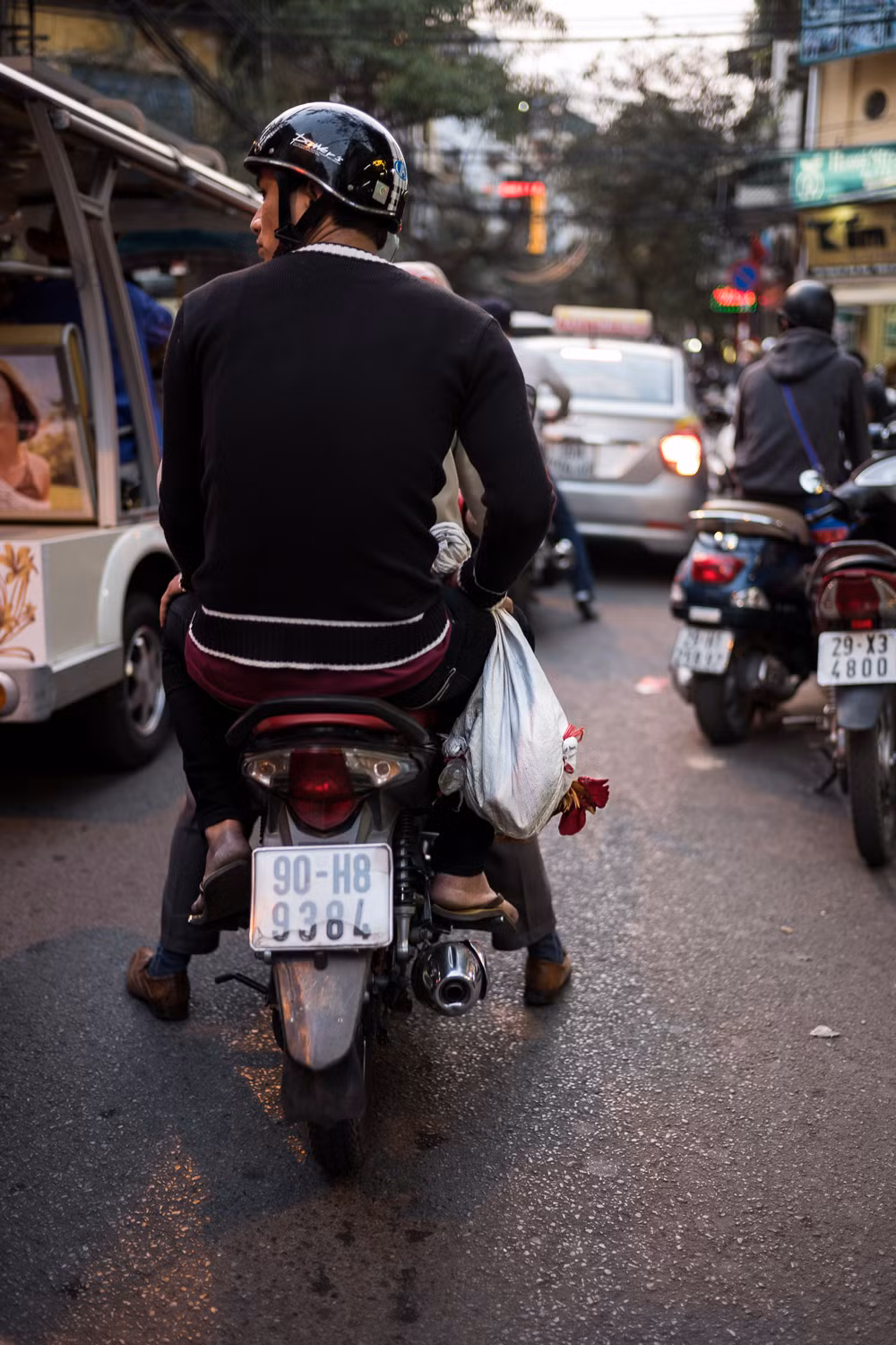 Chú gà tội nghiệp bị treo lủng lẳng trên xe máy ở phố cổ Hà Nội. Ảnh: Artem Chernov.