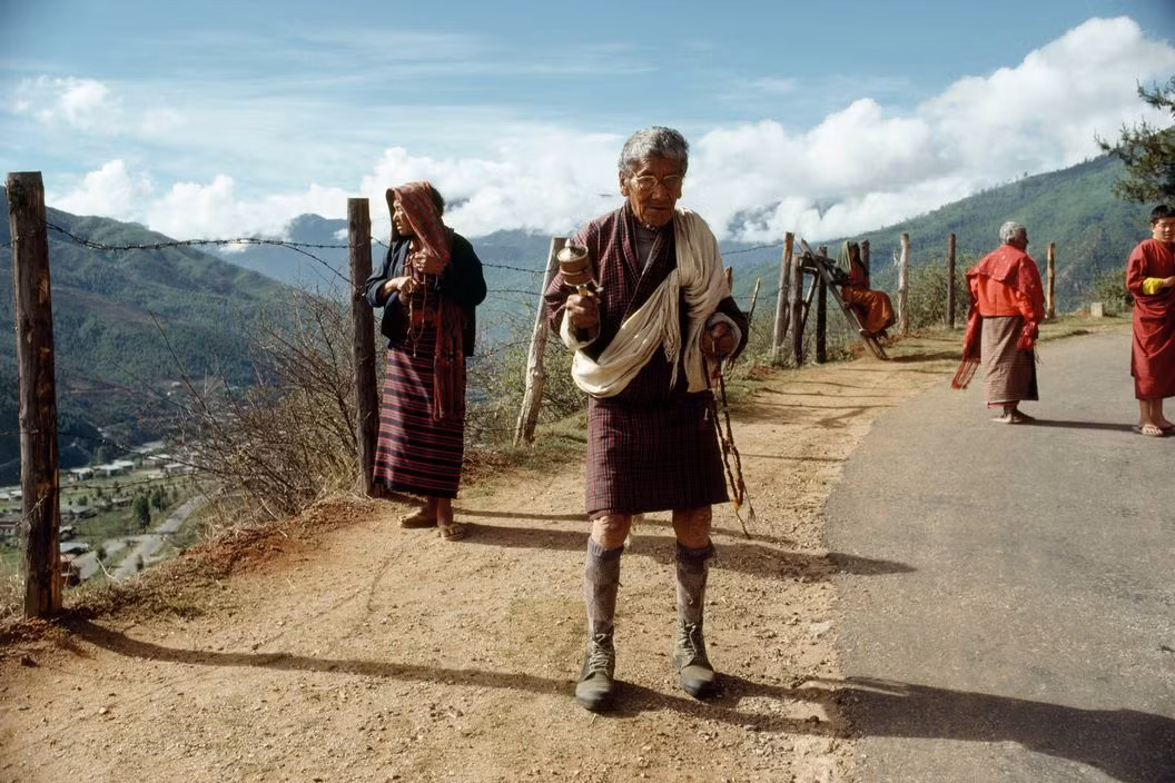 Một cụ ông cầm bánh xe cầu nguyện ven con đường núi. Ảnh: Martin Parr/ Magnum Photos.